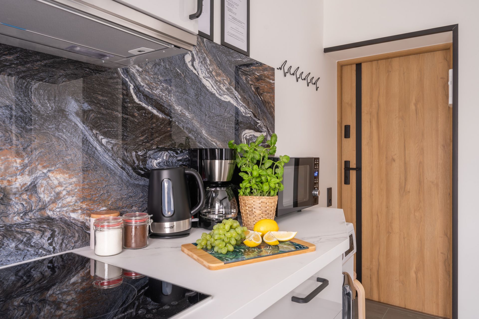 Compact fully equipped kitchenette with utensils, wine glasses and kettle in Riga rental apartment